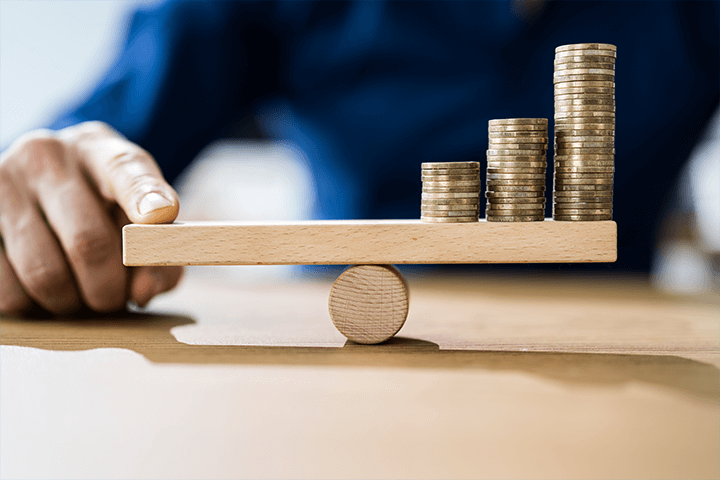 Moedas em uma balança de madeira representando investimentos atrelados a inflação